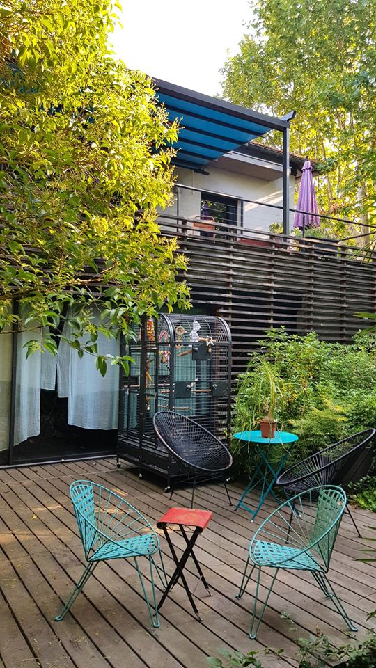 Aménagement extérieur d’une terrasse en bois à Alès, mobilier coloré et pergola moderne intégrée à la végétation